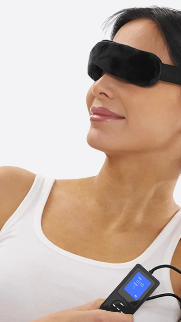 smiling woman wearing heated eye mask holding controller on grey background