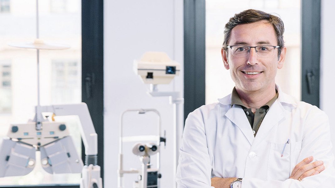 friendly dry eye specialist with ophthalmology equipment behind him